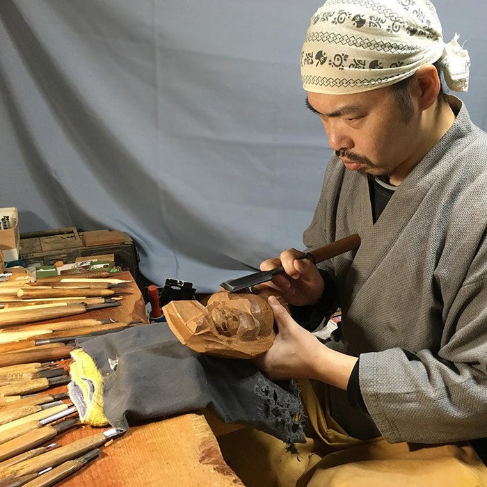 Artisan hand-carving a wooden sculpture with chisel, surrounded by carving tools in workshop | Ichii Itto Bori, Hiroshi Washizuka