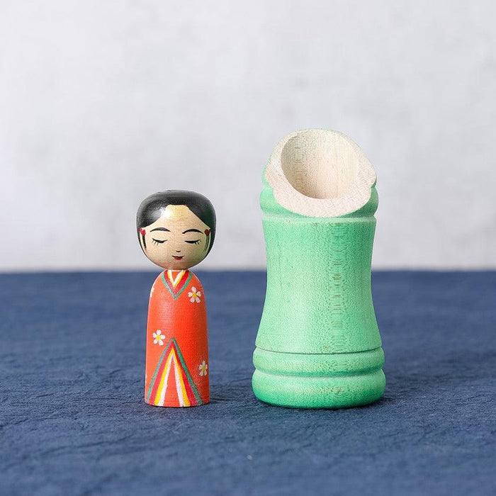 Princess Kaguya kokeshi wooden doll in red kimono beside green bamboo holder | Tsuchiyu, Fukushima