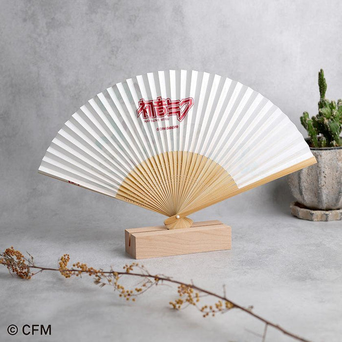 Hatsune Miku folding fan open on wooden stand, white paper with red kanji logo | Kyoto folding fan, Hatsune Koubou