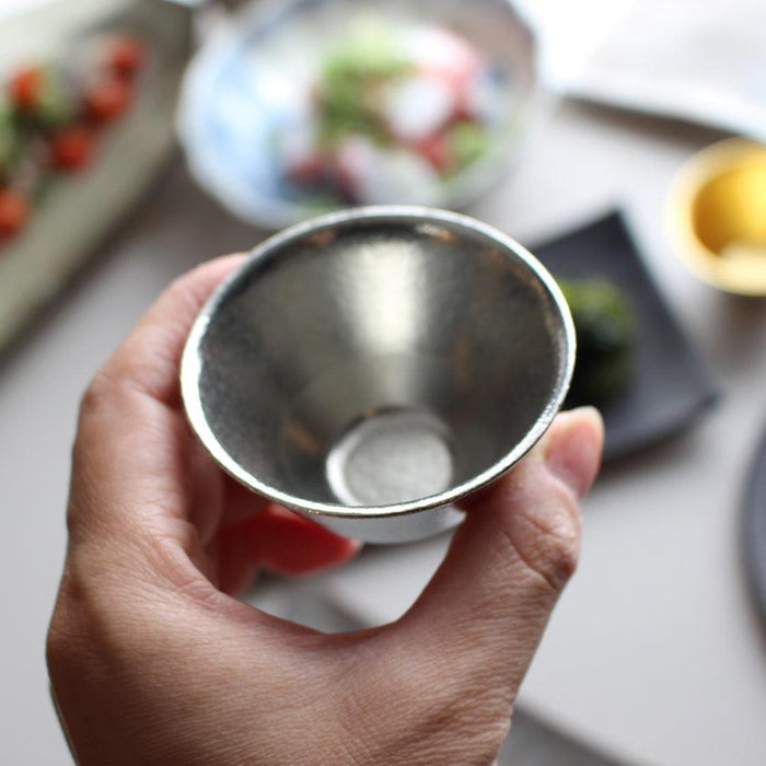 Hand holding a polished tin sake cup by Nousaku | Takaoka metalcraft, Japan