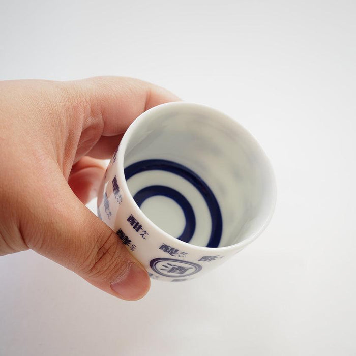 Hand holding a white porcelain sake cup with blue kanji text and spiral design | Mino ware, Marumo Takagi