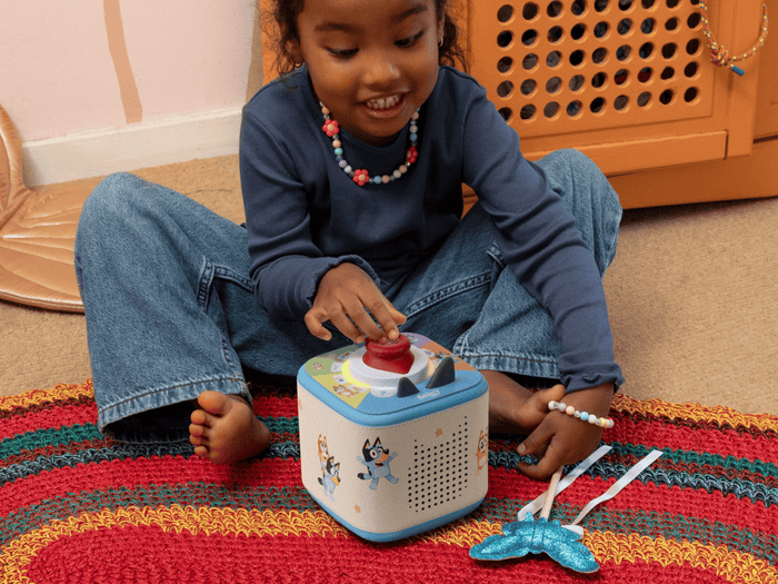child playing with tonieplay on a blue toniebox 2 with a bluey sleeve